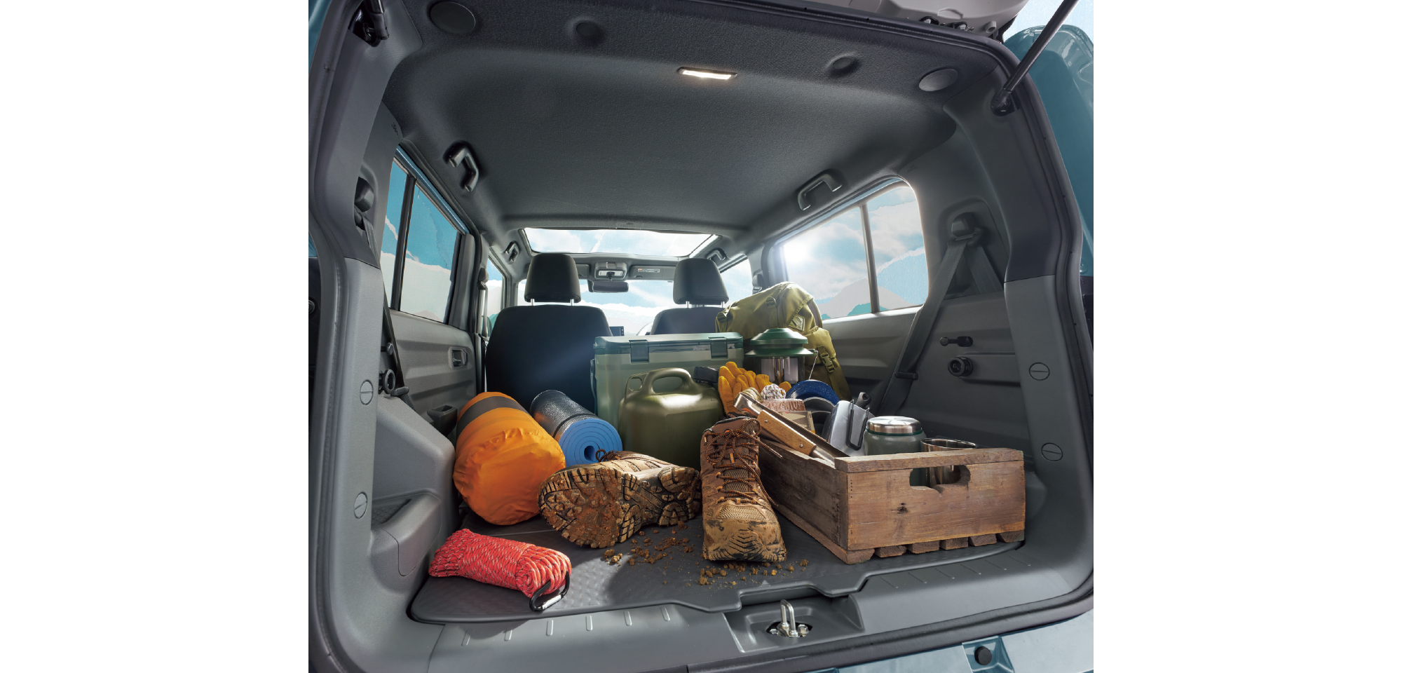 SUV trunk filled with camping gear: hiking boots, pantry items, containers, rope, and a wooden crate ready for a trip.