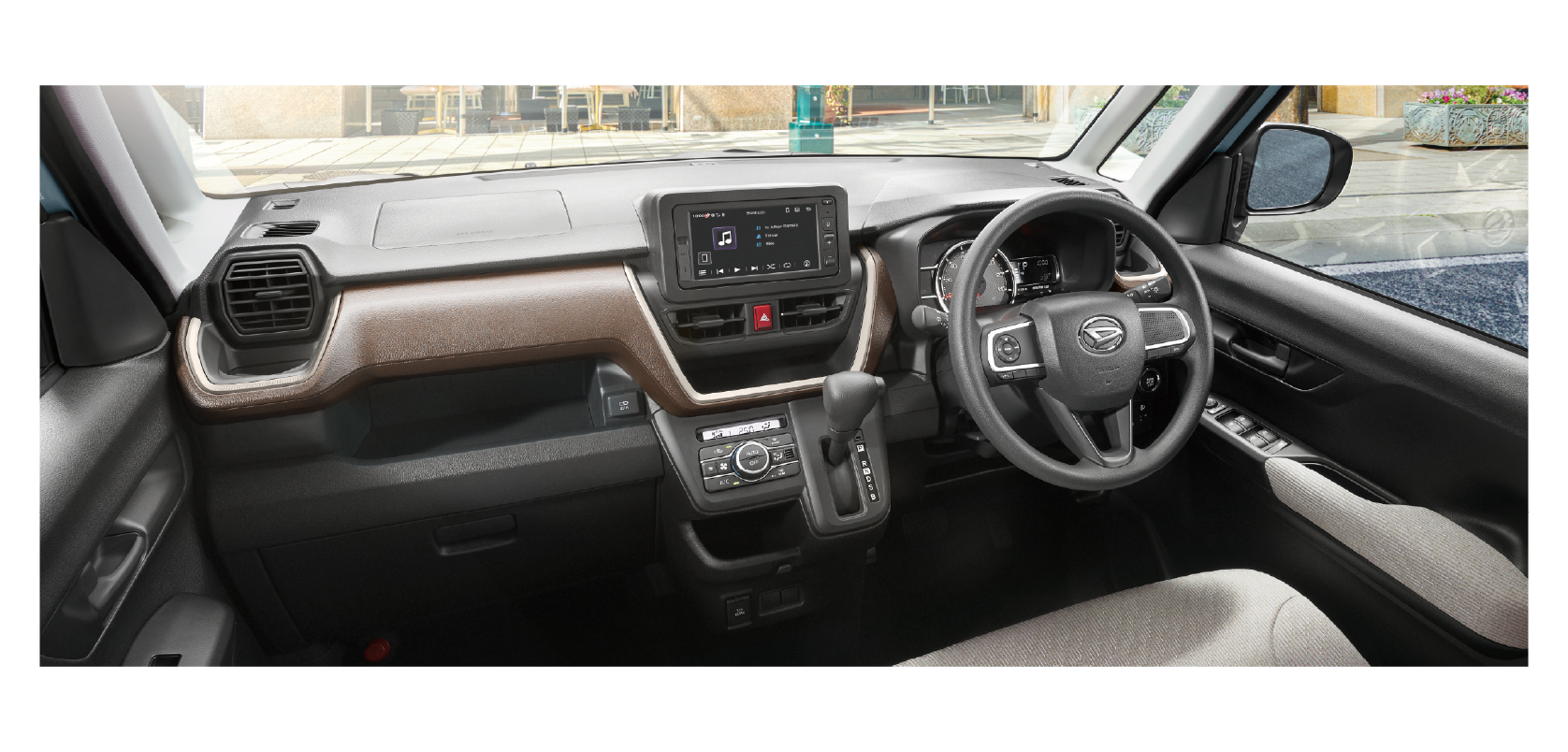 Right-hand-drive car interior with steering wheel, central touchscreen, brown dashboard trim, and gear selector